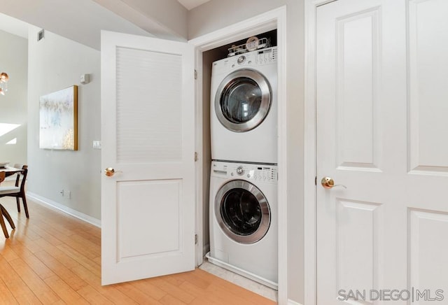 clothes washing area with stacked washer / drying machine and light wood-type flooring