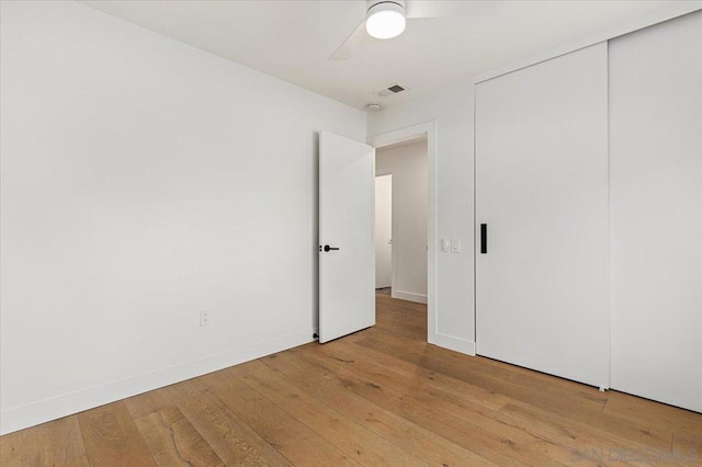 unfurnished bedroom with ceiling fan, a closet, and light wood-type flooring