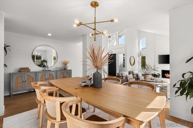 dining area featuring hardwood / wood-style flooring, a chandelier, and high vaulted ceiling