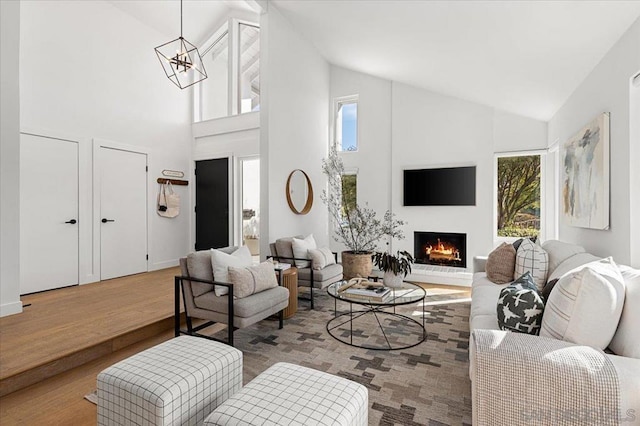 living room featuring high vaulted ceiling, light hardwood / wood-style flooring, and a notable chandelier