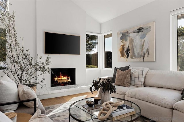 living room with lofted ceiling, a brick fireplace, and wood-type flooring