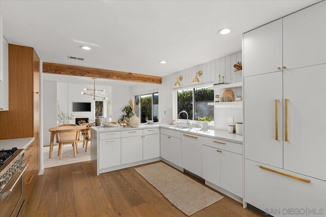 kitchen featuring sink, white cabinetry, high end appliances, decorative light fixtures, and dark hardwood / wood-style flooring