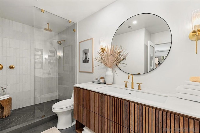 bathroom with vanity, toilet, and a tile shower