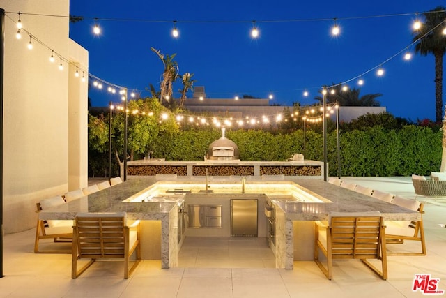 patio at night featuring an outdoor kitchen