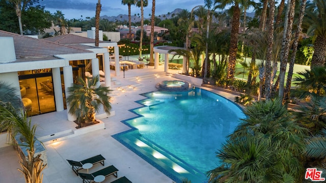 pool at dusk featuring an in ground hot tub, a bar, and a patio area