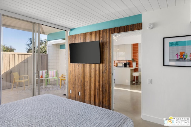 bedroom featuring wood walls, access to exterior, a wall of windows, and concrete floors