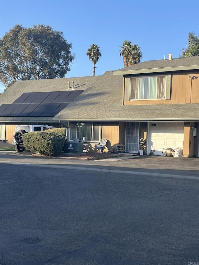 view of property featuring a garage and solar panels