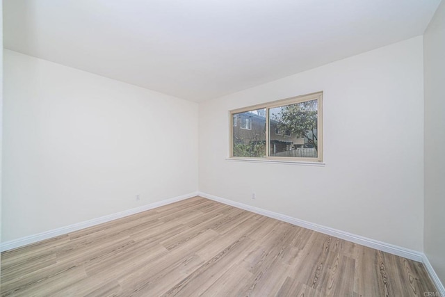 spare room with baseboards and light wood-style flooring