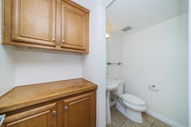 half bathroom with tile patterned floors, toilet, baseboards, and visible vents