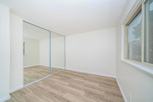 unfurnished bedroom with baseboards, a closet, and light wood-style floors