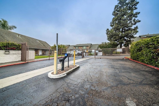 view of road with a gated entry, a gate, and curbs