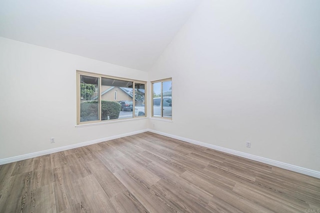 empty room featuring baseboards, high vaulted ceiling, and wood finished floors