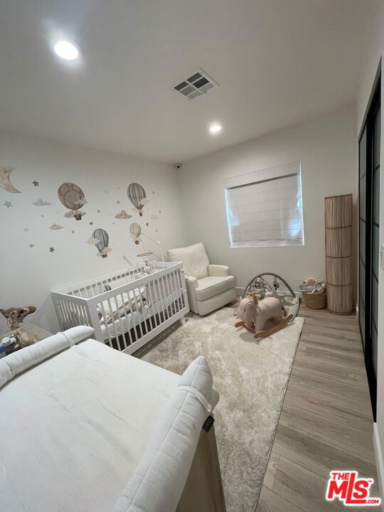 bedroom with a crib and light hardwood / wood-style floors