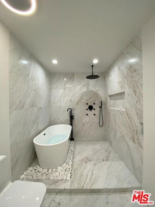 bathroom with toilet, tile walls, and a washtub