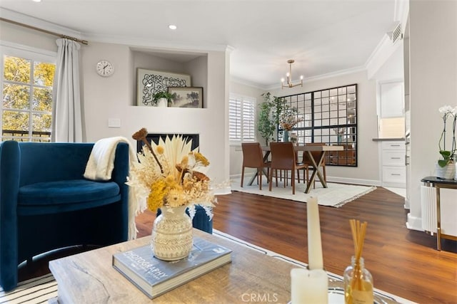 living room with hardwood / wood-style flooring, crown molding, and an inviting chandelier