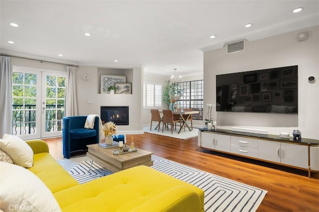 living room with crown molding, light hardwood / wood-style flooring, and a notable chandelier