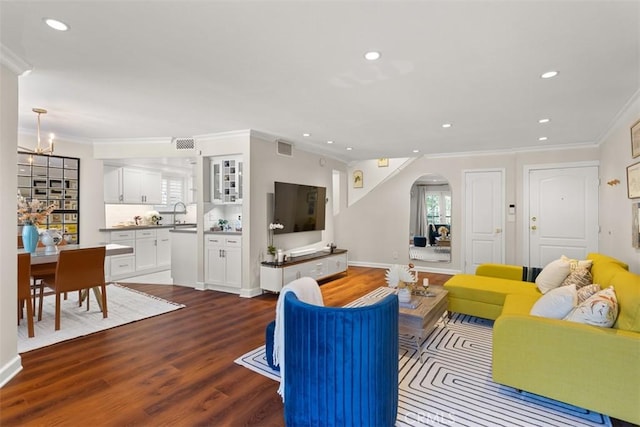 living room featuring hardwood / wood-style flooring, crown molding, a chandelier, and sink