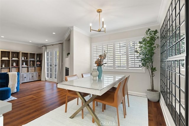 dining room with dark wood-type flooring, ornamental molding, and a notable chandelier