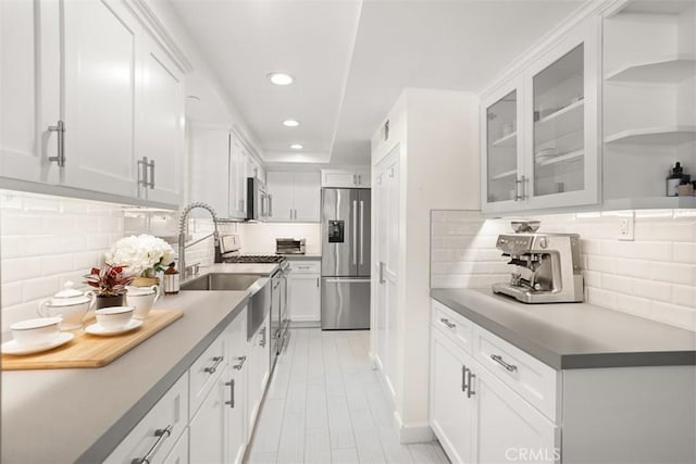 kitchen with stainless steel appliances, decorative backsplash, and white cabinets