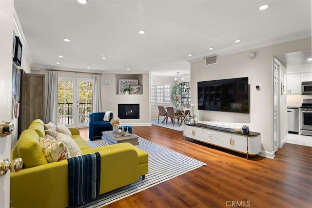 living room with ornamental molding, a healthy amount of sunlight, hardwood / wood-style floors, and a chandelier