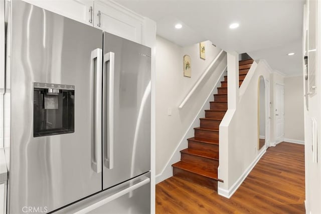 kitchen with stainless steel refrigerator with ice dispenser, dark wood-type flooring, and white cabinets