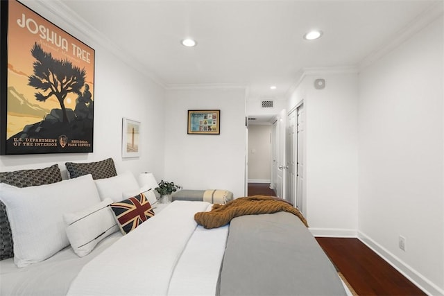 bedroom with hardwood / wood-style floors, crown molding, and a closet