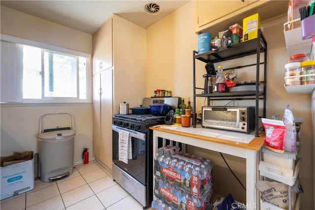 kitchen with tile counters, gas stove, and light tile patterned floors