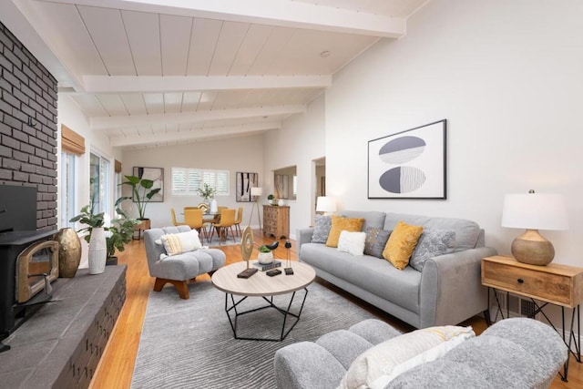 living room with lofted ceiling with beams, a wood stove, and hardwood / wood-style floors