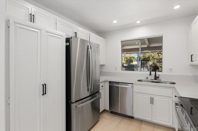 kitchen featuring stainless steel appliances, sink, light hardwood / wood-style flooring, and white cabinets