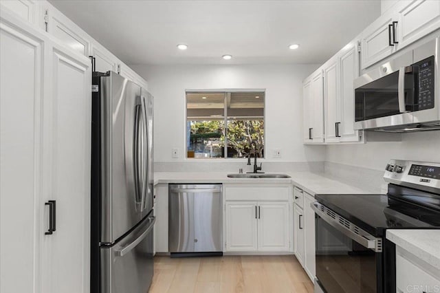 kitchen featuring white cabinetry, sink, light hardwood / wood-style flooring, and stainless steel appliances