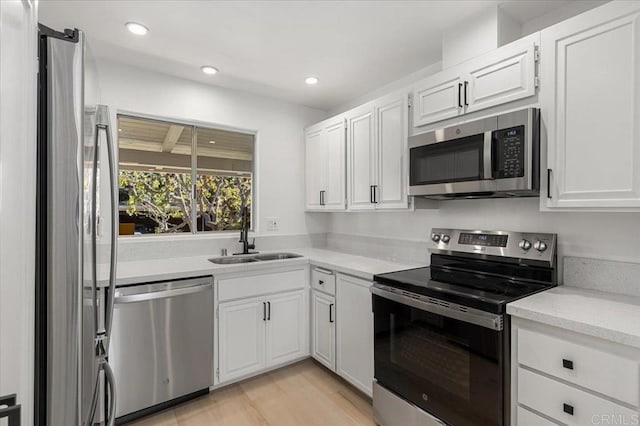 kitchen featuring stainless steel appliances, white cabinetry, sink, and light hardwood / wood-style floors