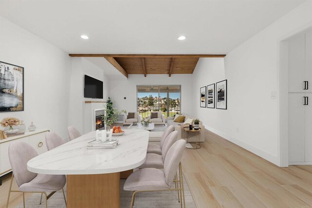 dining room featuring lofted ceiling with beams, wooden ceiling, and light hardwood / wood-style flooring