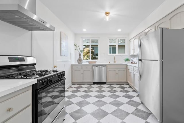 kitchen with stainless steel appliances, sink, and wall chimney range hood