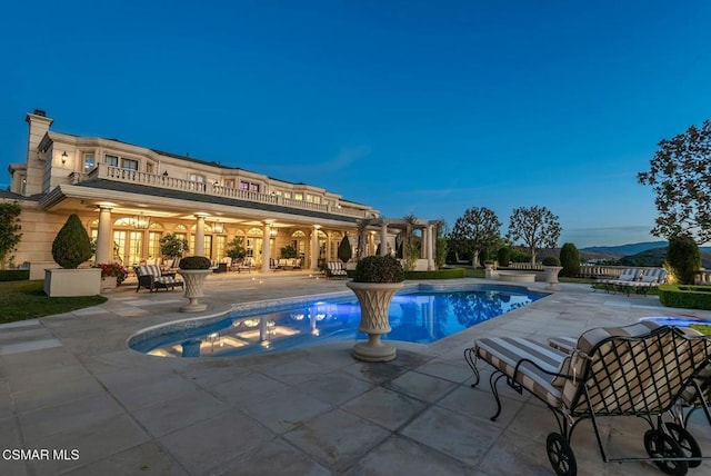 pool at dusk featuring a patio