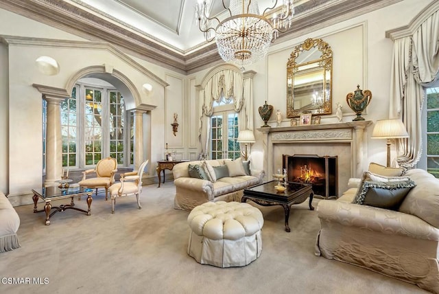 sitting room featuring crown molding, a high end fireplace, carpet floors, a chandelier, and ornate columns