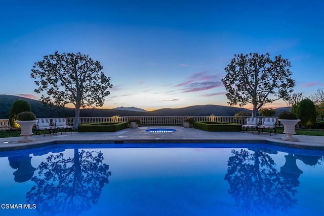 pool at dusk with a mountain view and a patio area