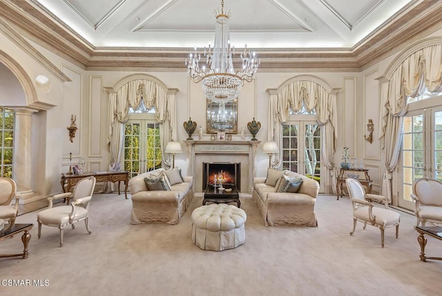 living area with a fireplace, carpet flooring, crown molding, an inviting chandelier, and french doors