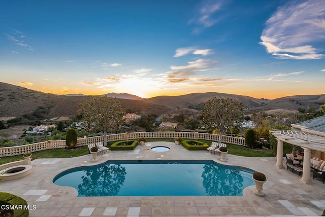 pool at dusk with a mountain view, a pergola, and a patio area