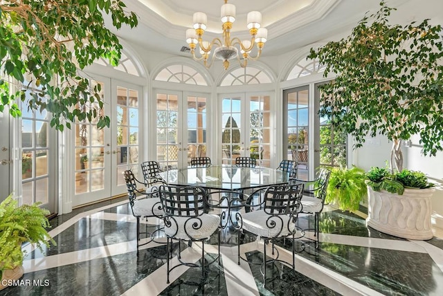 sunroom / solarium featuring french doors, a raised ceiling, and a chandelier