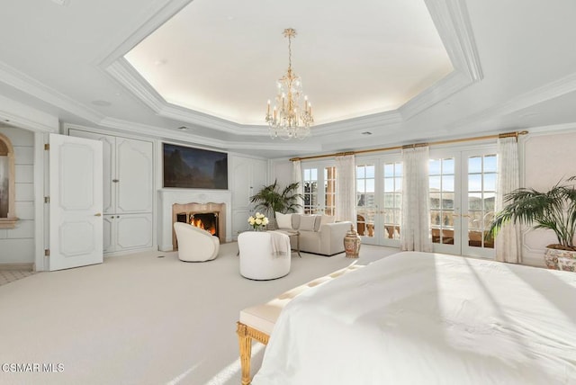 carpeted bedroom featuring french doors, ornamental molding, a raised ceiling, and a notable chandelier