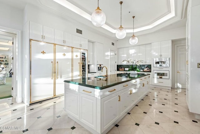 kitchen featuring built in refrigerator, a tray ceiling, and white cabinets