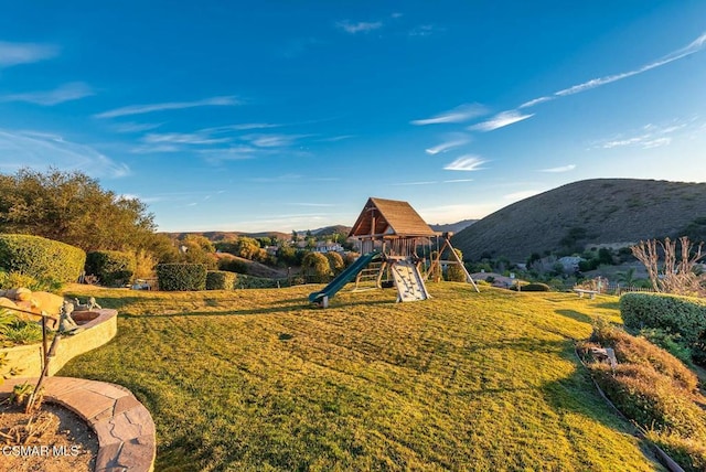 view of playground featuring a mountain view and a lawn