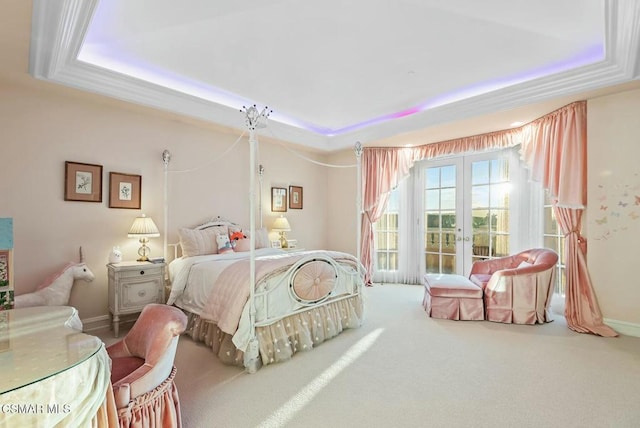 carpeted bedroom featuring a tray ceiling and french doors