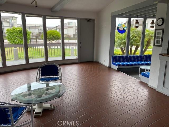 sunroom / solarium featuring beam ceiling