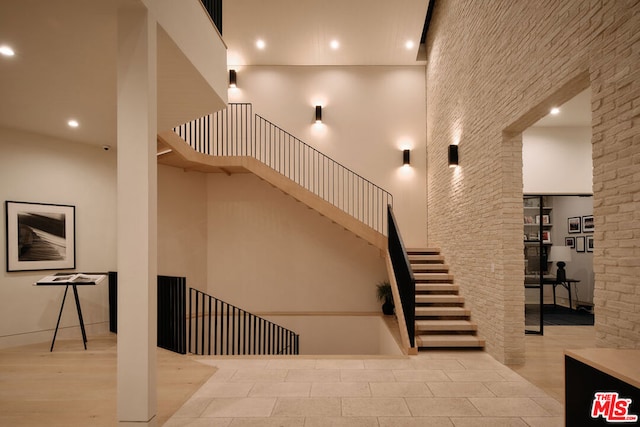 stairway featuring a high ceiling and hardwood / wood-style flooring