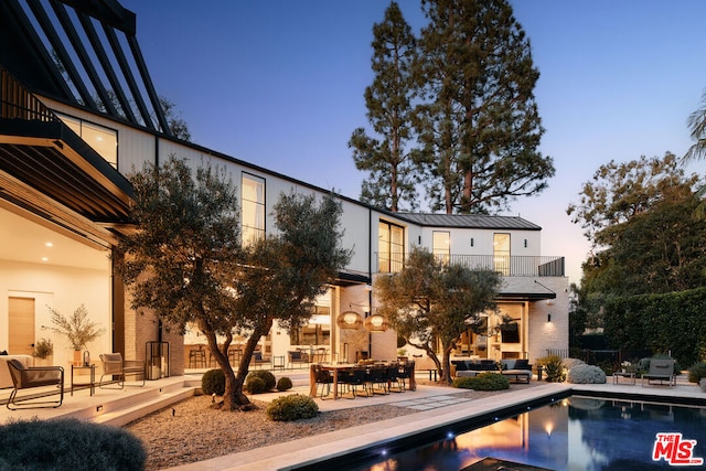 pool at dusk with outdoor lounge area and a patio area