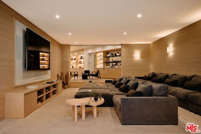 carpeted living room with wooden walls and built in features