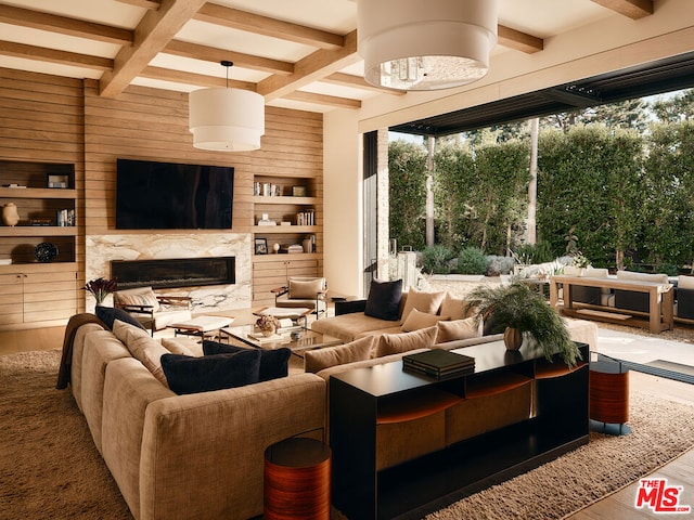 living room with a wealth of natural light, a high end fireplace, wooden walls, and hardwood / wood-style flooring