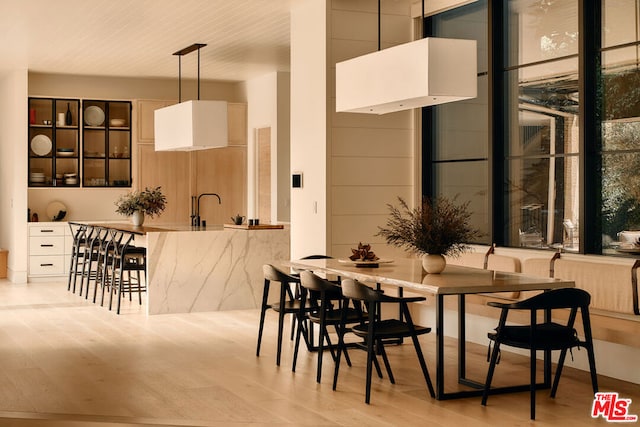 dining space with sink, light hardwood / wood-style floors, and a wall of windows