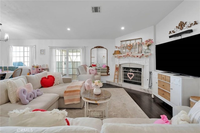 living room with wood-type flooring, plenty of natural light, and a high end fireplace